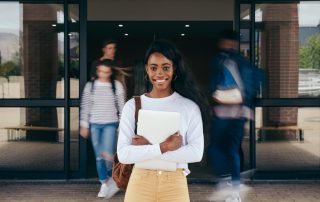 student in front of college entrance